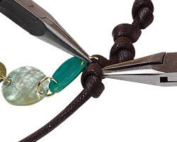 Pliers holding a jump ring around a knotted cord
